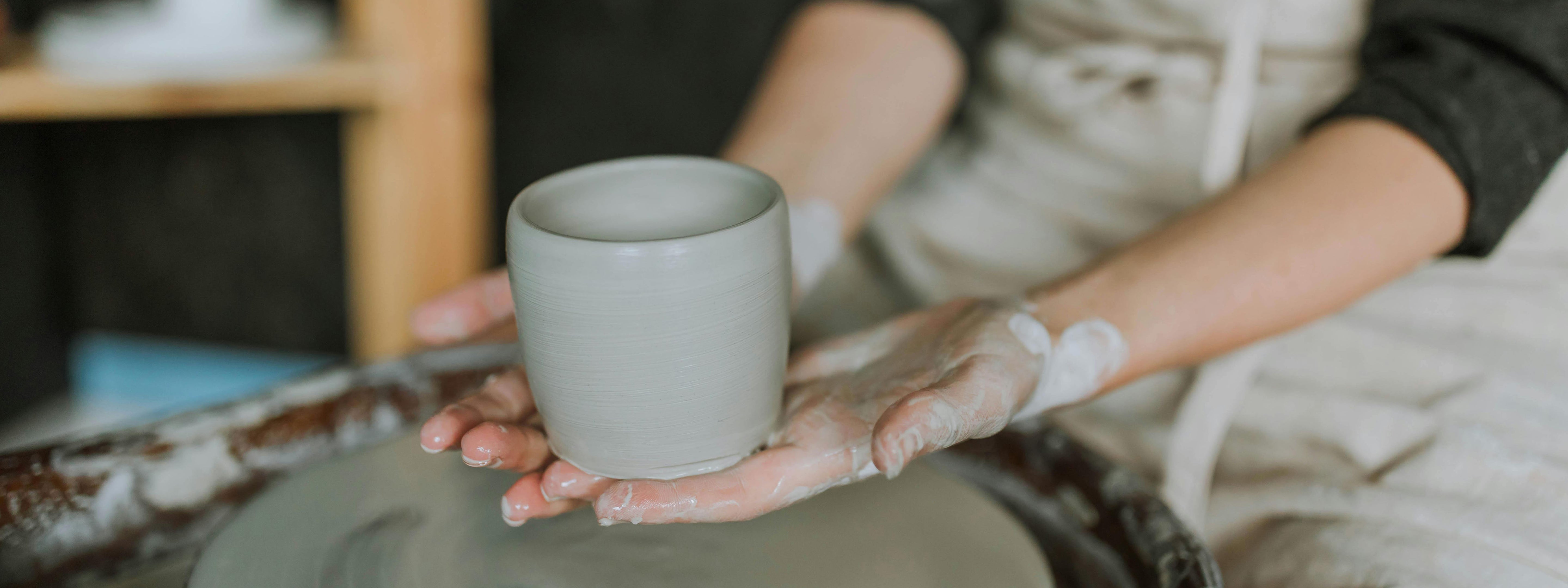 a freshly thrown clay cup in the potters hands.
