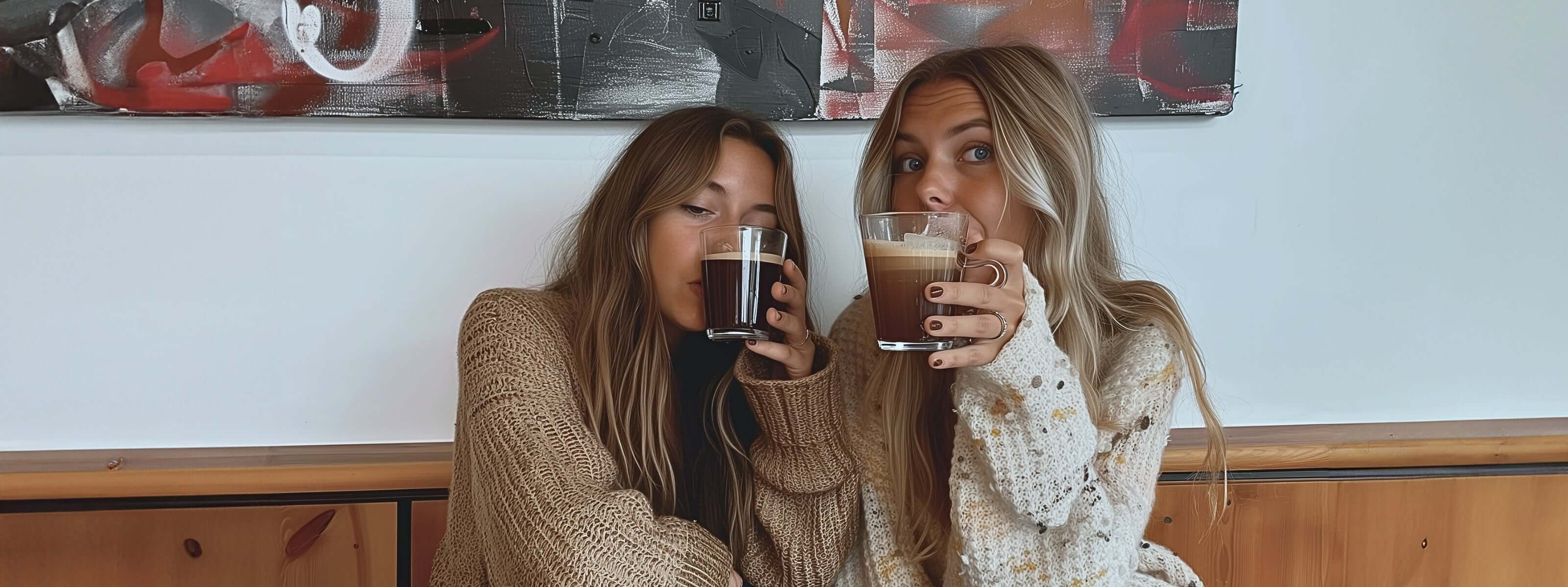 two young girls sharing confidences while drinking mugs of coffee.