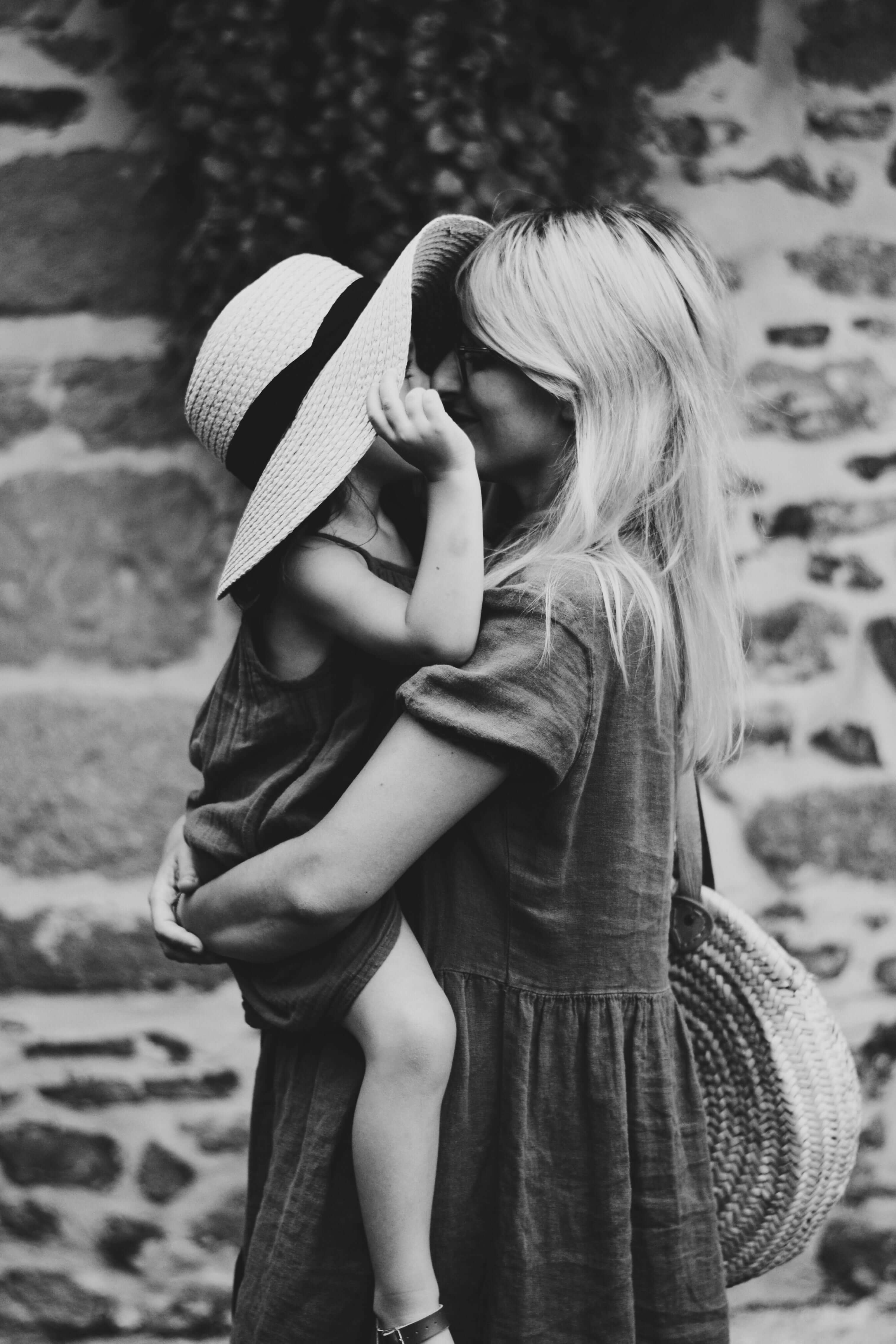 mother holding and kissing daughter in black and white.